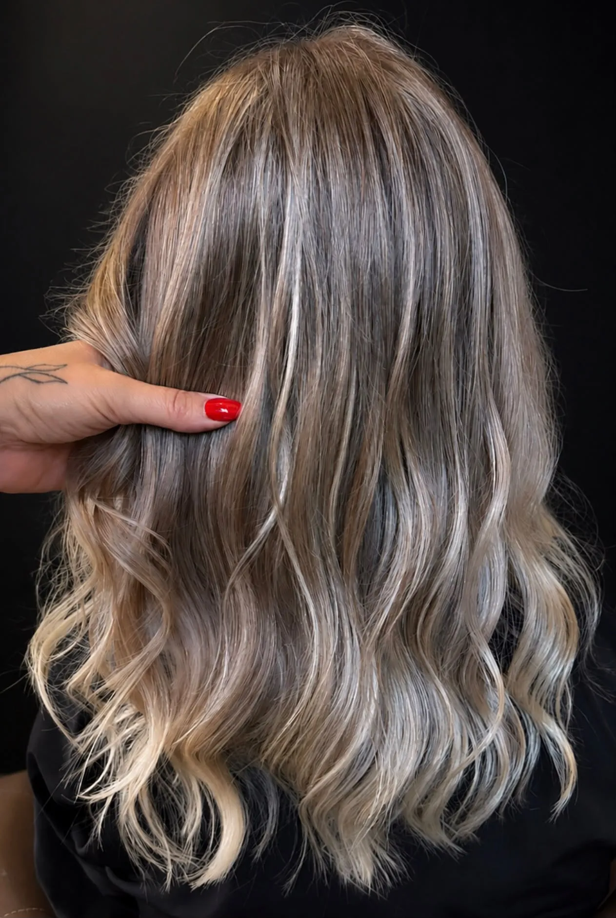Capelli mossi con riflessi beige e sabbia su sfondo scuro
